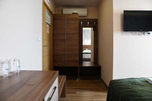 a bedroom with a bed and a dresser with a mirror at Hotel Garden in Novi Sad