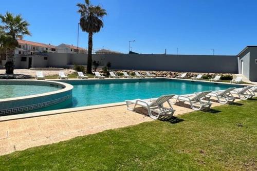 een zwembad met ligstoelen in het gras bij Casa Papillon in Sagres