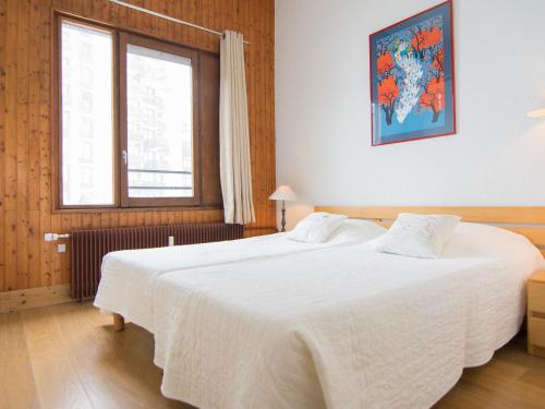 une chambre avec deux lits avec des draps blancs et une fenêtre dans l'établissement 2P spacieux au Val-Claret, balcon sud/ouest, à 500m des pistes, wifi, animaux admis - FR-1-449-155, à Tignes