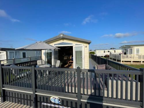 a deck with a house with an umbrella at Millfields Holiday Park - Diamond Deluxe - Coastal Caravan Breaks in Ingoldmells