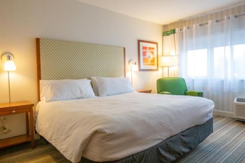 a bedroom with a large bed and a green chair at Holiday Inn Express Columbus Airport Easton in Columbus