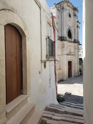 an old building with a door and a church at Casa Santa Chiara - Affitti Brevi Italia in Monte SantʼAngelo