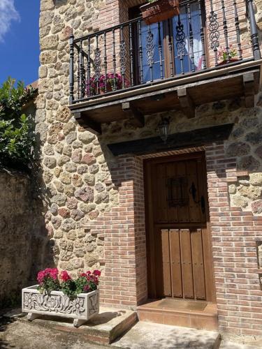 a building with a door and a balcony with flowers at La Casa de Fefita (Stone house in a privileged environment 35 km from Bilbao) in Villanueva de Mena