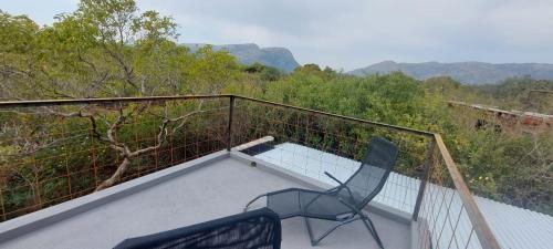 a balcony with a chair and a view of the mountains at Hartbeest Eco Bush Lodge 3 in Hartbeespoort