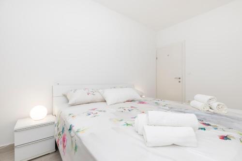 a white bedroom with a white bed with flowers on it at Apartments Tony in Mali Lošinj