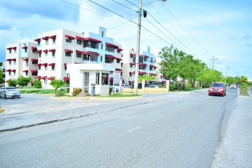 a red car driving down a street next to a white building at Moderno apartamento para tu estancia in Licey