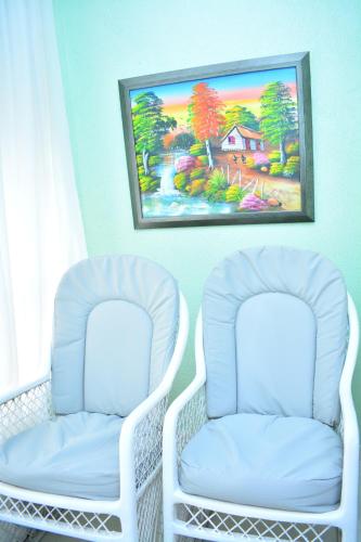 two white chairs in a room with a painting on the wall at Moderno apartamento para tu estancia in Licey