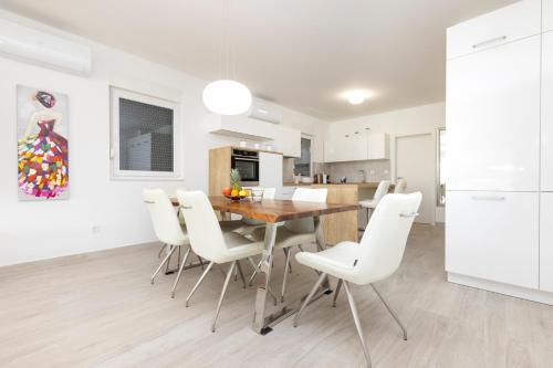 a kitchen and dining room with a wooden table and white chairs at Apartments Tony in Mali Lošinj