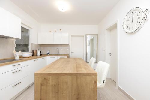 a kitchen with a wooden table and a clock on the wall at Apartments Tony in Mali Lošinj