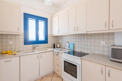 a kitchen with white cabinets and a sink and a window at Sealit Deluxe Apartment in Drios