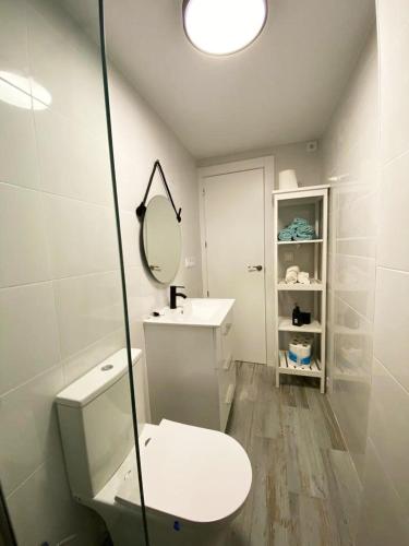 a white bathroom with a toilet and a mirror at Malvarrosa Private Rooms in Shared Apartment in Valencia