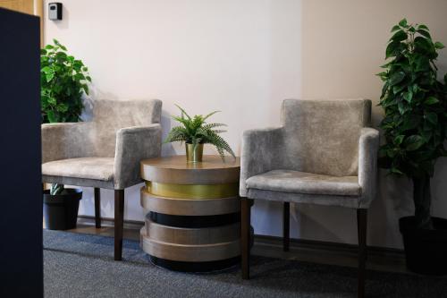 two chairs and a table in a room with plants at Hotel Garden in Novi Sad