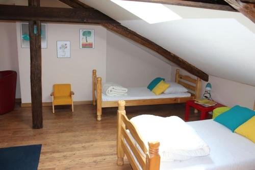 Cette chambre mansardée comprend deux lits et une chaise. dans l'établissement Maison de campagne avec terrain, à Mialet