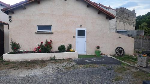 een huis met een witte deur en wat bloemen bij Le mistral auvergnat in Montaigut-le-Blanc