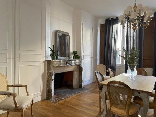 a dining room with a table and a fireplace at Hôtel particulier Champenois in Chalons en Champagne