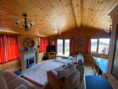 una sala de estar con sofás y una chimenea en una cabaña en Surf Lodge en West Down