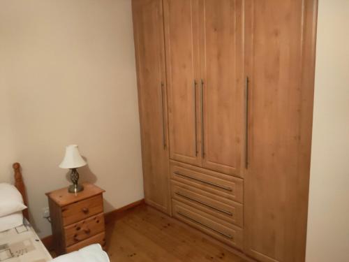 a bedroom with a large wooden cabinet next to a bed at House in Miltown Malbay