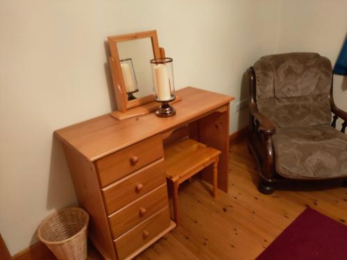 a wooden dresser with a mirror and a chair at House in Miltown Malbay