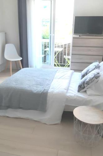 ein weißes Schlafzimmer mit einem Bett und einem Fenster in der Unterkunft Joli studio centre de La Baule in La Baule
