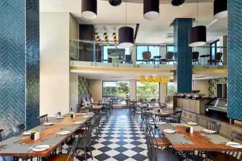 a restaurant with wooden tables and chairs and a checkered floor at V and I at The Regency Apartment Hotel in Pretoria