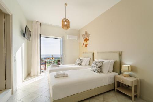 two beds in a bedroom with a view of the ocean at Drita Studios & Apartments in Svoronata