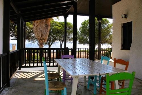 una mesa de madera y sillas coloridas en el patio en The Sisters Beach House, en Vathírrevma