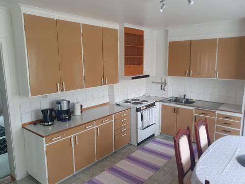 a kitchen with brown cabinets and a white stove top oven at Mysig lägenhet för resande in Stocka