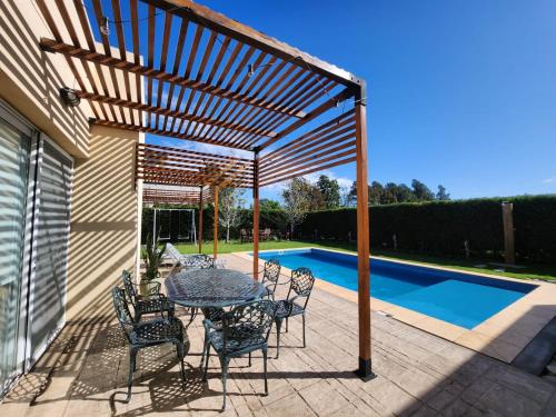 a wooden pergola with a table and chairs on a patio at Casa en Club de Campo. Parque y Pileta. in San Nicolás de los Arroyos