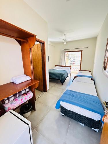 a room with three beds and a desk at Pousada Serra Branca in São Thomé das Letras