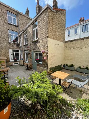 a patio with a wooden table in front of a building at Villa Artiz in Dunkerque