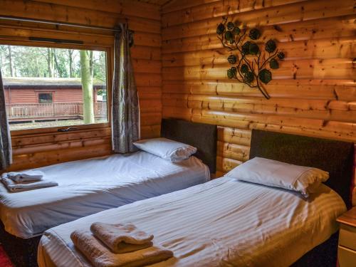 two beds in a log cabin with a window at Larch Lodge - Uk37187 in Legbourne
