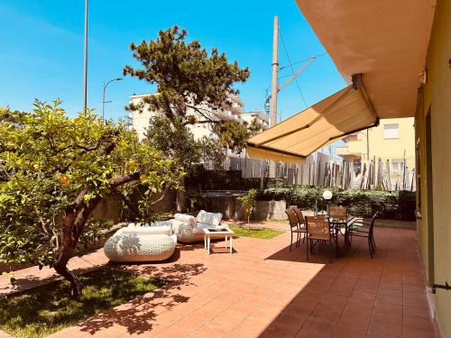 een patio met een tafel en stoelen en een boom bij Siliade Apartment in Montesilvano