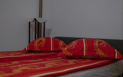 two red pillows sitting on top of a bed at Pensiunea La Maison Verte in Pietroasa