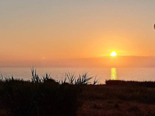a sunset over the ocean with the sun setting at Sunset House Porto de Barcas - 3 rooms & Terrace in Lourinhã