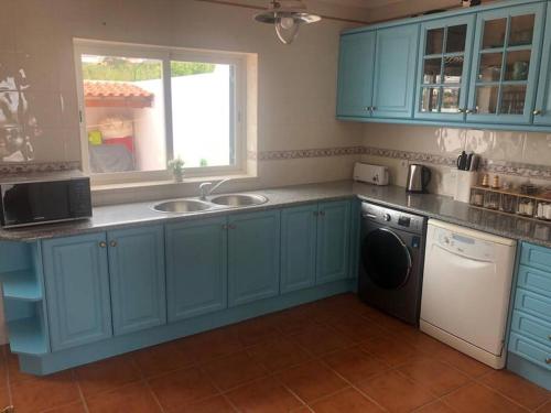a blue kitchen with a sink and a dishwasher at Sunset House Porto de Barcas - 3 rooms & Terrace in Lourinhã