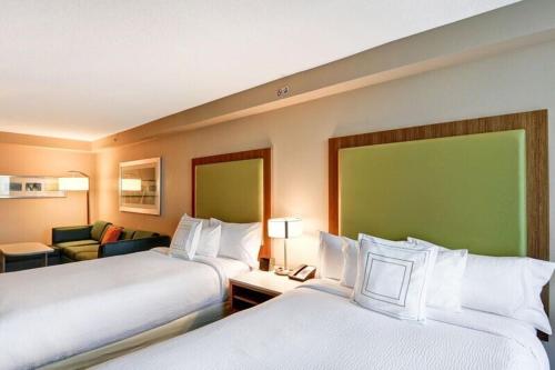 a hotel room with two beds and a couch at SpringHill Suites by Marriott Orlando Lake Buena Vista South in Kissimmee