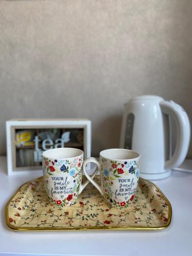 two coffee cups sitting on a tray on a table at Mira - Mira pokoje z widokiem na jezioro in Chmielno