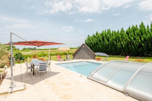 une piscine avec une table et un parasol dans l'établissement Gîte Le Campane - Piscine partagée Borne recharge véhicule 22kwh, à Laujuzan