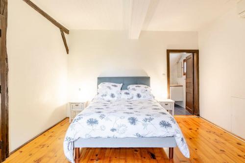 - une chambre blanche avec un lit doté d'une tête de lit bleue dans l'établissement Gîte Le Campane - Piscine partagée Borne recharge véhicule 22kwh, à Laujuzan