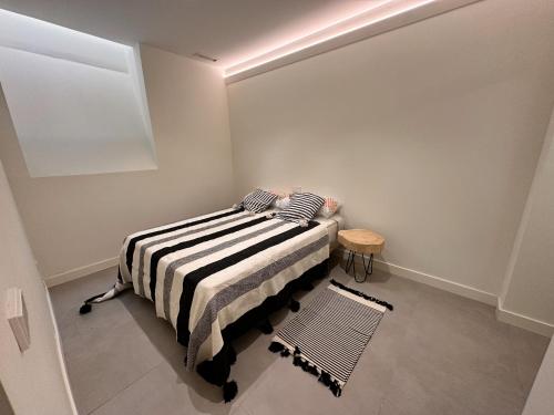 een slaapkamer met een bed met een gestreepte deken bij Segovia in Madrid