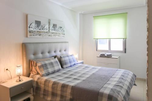 1 dormitorio con 1 cama con manta a cuadros y ventana en Elsa's Rotonda Apartment, en Cabo Roig