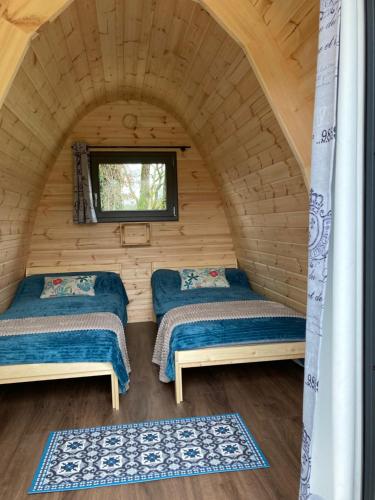 two beds in a log cabin with a window at POD nature in Chazelles