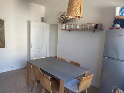 une cuisine avec une table, des chaises et un réfrigérateur dans l'établissement Maison familiale - centre d'Uzès, à Uzès