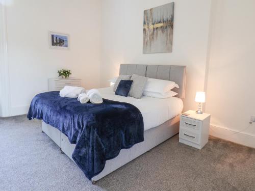 a bedroom with a large bed with a blue blanket at The Garden Apartment in Yarm