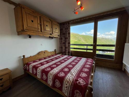 une chambre avec un lit et une grande fenêtre dans l'établissement Appartement rénové 3 pièces pour 6 pers, balcon, 2 sdb, proche ascenseur, skis, qualité 4 flocons - FR-1-452-203, aux Menuires