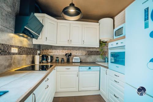 una cocina con armarios blancos y fregadero en APPART T3, en Bagnols-sur-Cèze