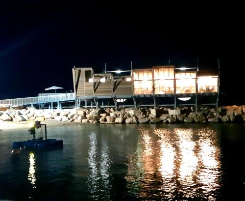 a building with lights on the water at night at Little House in San Salvo