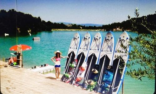 a woman standing on a dock next to a group of water skis at Chambre Indépendante Piscine, Parc, Cuisine... in Brézilhac