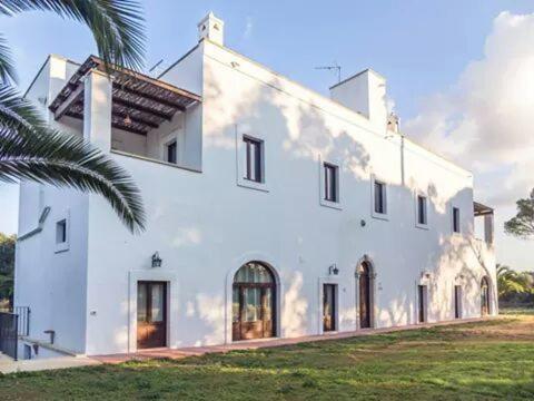 a white building with a palm tree in front of it at Tenuta Afra in Squinzano