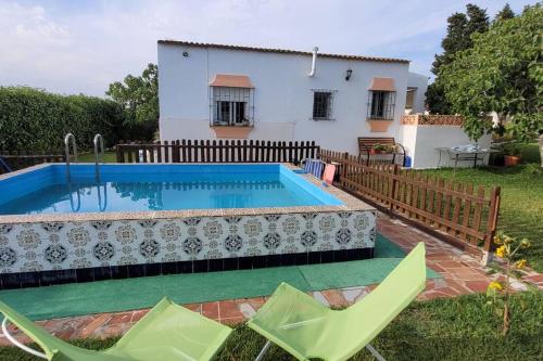 - une piscine dans une cour avec des chaises et une maison dans l'établissement Casa con piscina privada y jardín, à Chiclana de la Frontera